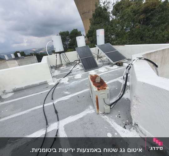 איטום גג עם חומר לבן, כבלים ומיכלים.